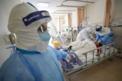Trabajadores médicos fuertemente protegidos atienden a pacientes de coronavirus en la ciudad china de Wuhan, el 17 de febrero de 2020.