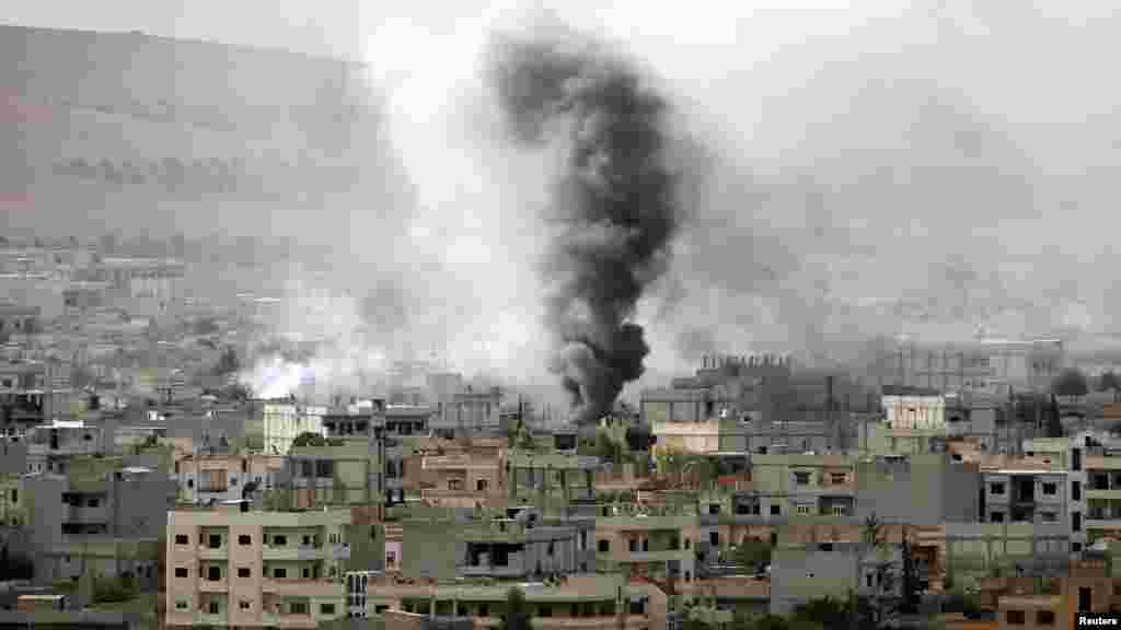 Smoke rises from the Syrian town of Kobani, seen from near the Mursitpinar border crossing on the Turkish-Syrian border in the southeastern town of Suruc in Sanliurfa province, Oct. 12, 2014.
