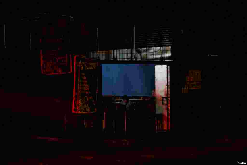 Una mujer se sienta dentro de una tienda iluminada con lámparas recargables durante un apagón nacional por mantenimiento en el sistema eléctrico del país durante la noche del miércoles, en Puyo, Ecuador, el 18 de septiembre de 2024. REUTERS/Karen Toro REFILE - REPETICIÓN DE CALIDAD 