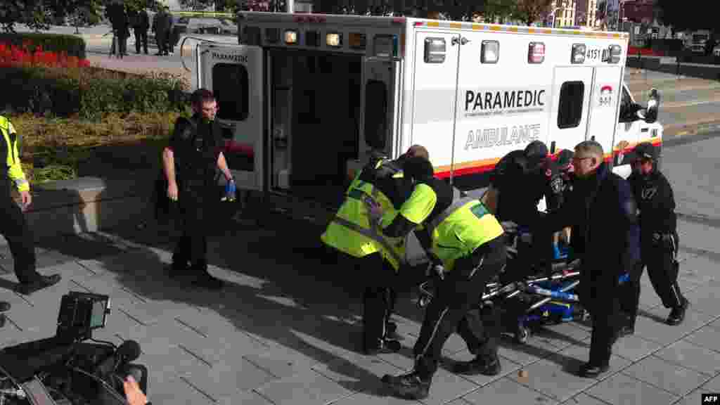 La police et les ambulanciers transportent un soldat canadien blessé à Ottawa, Canada, le 22 octobre 2014..
