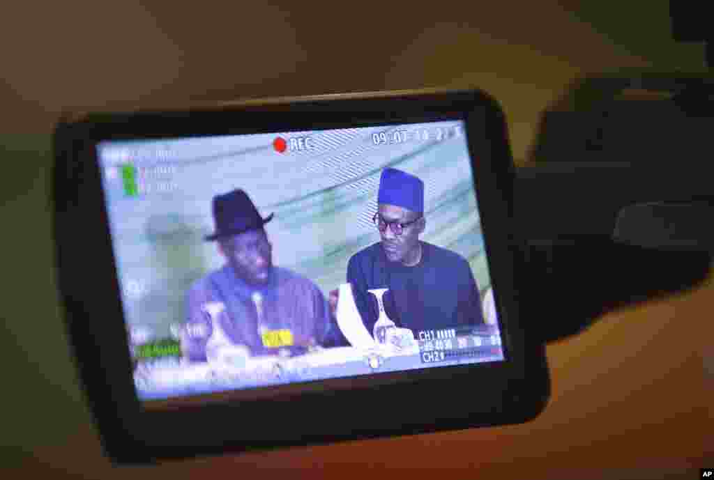 Vus à travers l'écran d'une caméra, le candidat de l'opposition, le général Muhammadu Buhari, à droite, et le président Goodluck Jonathan du Nigeria, à gauche, se préparent à renouveler leur engagement à organiser des élections pacifiques "libres, justes et crédibles", dans un hôtel de la capitale Abuja, Nigeria jeudi 26 mars 2015. 