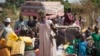 FILE - Refugees who fled the recent violence in South Sudan and crossed the border into Uganda carry their belongings as they await transportation from a transit center in the town of Koboko to a nearby settlement in Arua District, in northern Uganda, Jan 6, 2014.