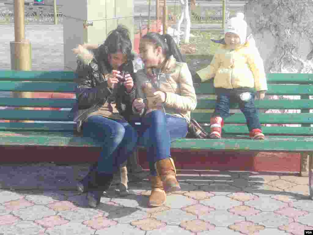 Yosh qizlar iliq oftob nuri ostida o'tiribdi.
