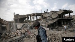 FILE - An Afghan policeman walks at the site a truck bomb blast in Kabul, Aug. 7, 2015. 