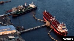  FILE - Oil tankers Qi Lin Zuo of China and Sti-Matador, left, stand attached to mooring stations near a refinery in Bayonne, New Jersey, Aug. 24, 2011. Crude oil is among the U.S. products China has said it will impose tariffs on but has yet to announce a date.