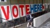 FILE - A voter passes a large sign before voting in Minneapolis.