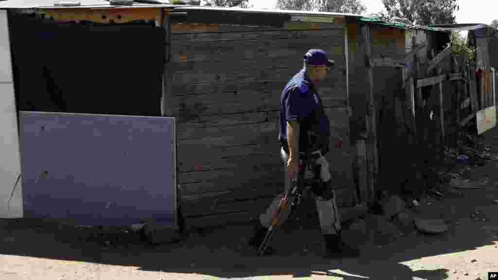 Un policier se promène entre les cabanes dans un bidonville à Germiston, à l'est de Johannesburg, Afrique du Sud, jeudi 16 avril 2015.