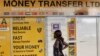 A woman looks at the closed doors of a money-transfer service in Nairobi, Kenya Wednesday, April 8, 2015. The Kenya government said Wednesday that it was freezing the accounts of a list of companies and individuals identified because of suspicious transactions, with the list including some money-transfer services dealing in remittances to Somalia. (AP Photo/Khalil Senosi)