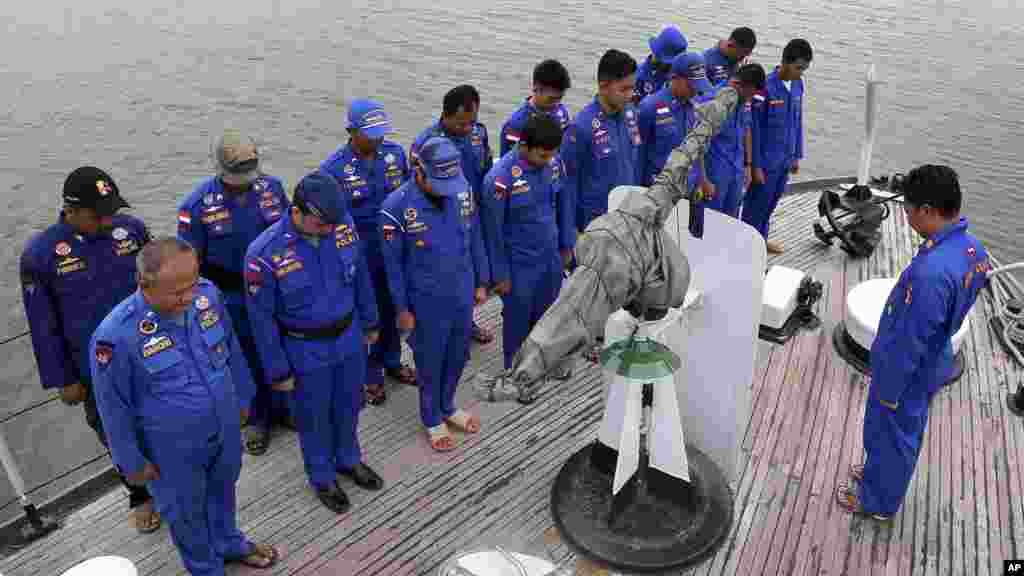 Les membres de la police maritime de l'Indonésie prient à bord d'un navire de recherche et de sauvetage avant une opération de recherche de l'avion d'AirAsie disparu, au port de Pangkal Pinang dans l'île de Sumatra, en Indonésie, le 29 décembre 2014.