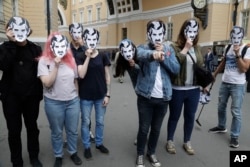 Arhiva - Ljudi nose maske sa likom Velikog brata iz novele Džordža Orvela 1984. tokom mitinga podrške većim medijskim sloboddama u Sankt Peterburgu, Rusija, 16. jula 2017.