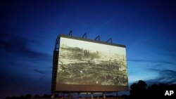En esta fotografía de archivo del miércoles 26 de mayo de 2021, se ve una imagen de la devastación tras la Masacre de Tulsa en una pantalla de autocine que exhibe el documental "Rebuilding Black Wall Street".
