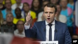 FILE - Supporters of French presidential candidate Emmanuel Macron hold placards as he speaks during a campagin rally in Lyon, central France, Feb. 4, 2017.