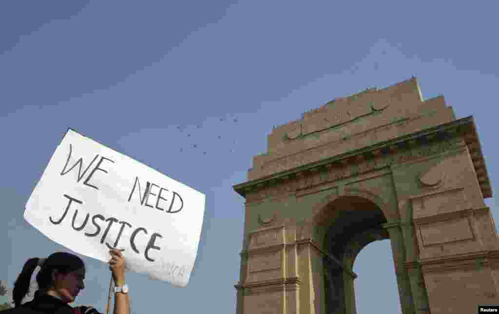Seorang demonstran memegang plakat bertuliskan "Kami Ingin Keadilan" di depan gerbang India Gate dalam protes yang diadakan oleh berbagai organisasi perempuan di New Delhi (21/12).