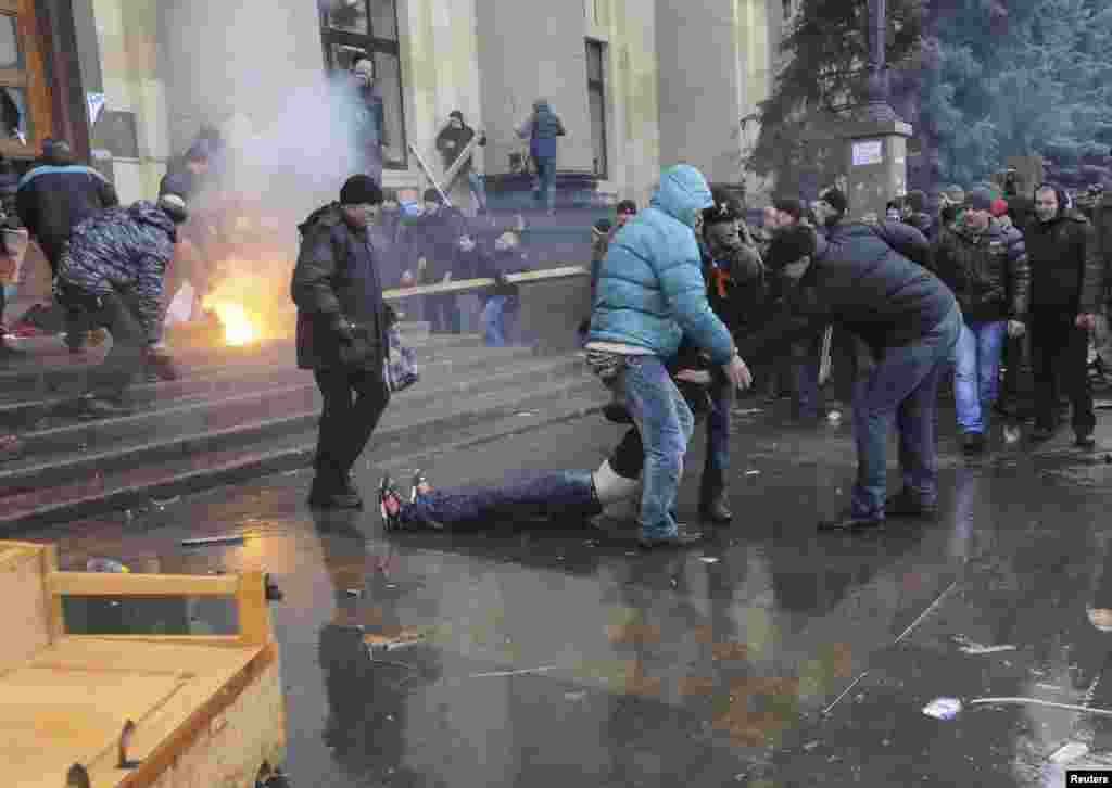 In central Kharkiv, pro-Russian protesters drag a wounded man during clashes with supporters of Ukraine's new government as pro-Russia activists tried to seize the regional governor's headquarters, Interfax news agency said.