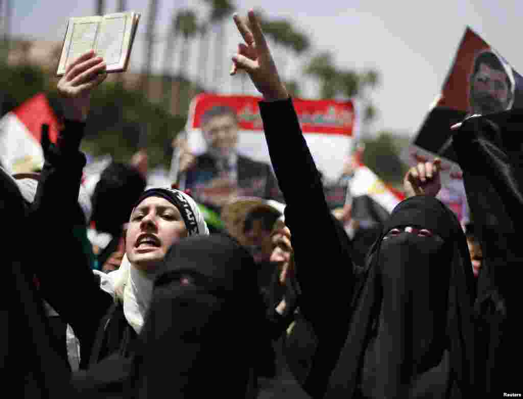 A supporter of former Egyptian President Mohamed Morsi holds up a copy of the Koran as she and others march near Cairo University after Friday prayers in Cairo, July 5, 2013. 