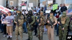 FILE - In this May 2, 2020, fphoto, people, including those with the boogaloo movement, demonstrate against business closures due to concern about COVID-19, at the State House in Concord, N.H.