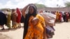 A woman, who fled amid a drought, carries her baby at a makeshift camp for displaced people on the outskirts of Mogadishu, Somalia on Tuesday, Sept. 26, 2023.