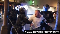  Les policiers de Portland retiennent un homme qui était visé par des tirs de balles le 29 août 2020 à Portland, Oregon. (Photo: Nathan HOWARD / GETTY via AFP)