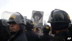 Demonstrators shout slogans against a medical pardon to former President Alberto Fujimori with photographs of people slain during his decade in power, as they confront riot police in Lima, Peru, Monday, Dec. 25, 2017.