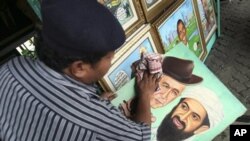 Indonesian painter S. Wito wipes his painting of Osama bin Laden and former U.S. President George Bush at his street-side studio in Jakarta, Indonesia, May 2, 2011.