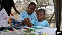 Un homme aide un enfant autiste à peindre lors de la Journée mondiale de l'autisme, à Abidjan le 2 avril 2017.