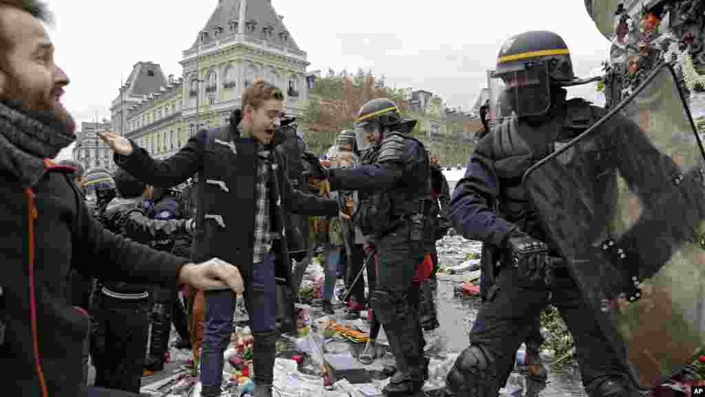 Des policiers se battent avec les militants qui manifestent en marge de la Conférence sur le climat de Paris, à la place de la République, sur les bougies et des fleurs déposées en hommage des victimes des attentats de Paris, 29 novembre 2015. 