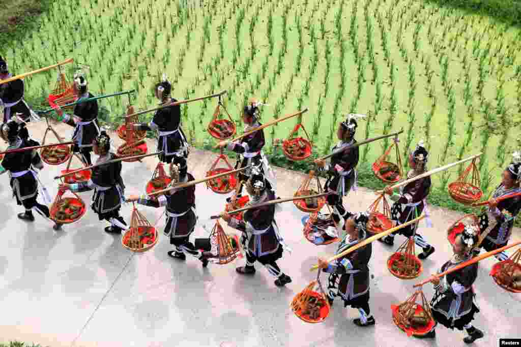 Dong ethnic minority women carry packages of "zongzi", or rice dumpling, during a local festival in a village at Liping County, Guizhou Province, China, June 17, 2017.