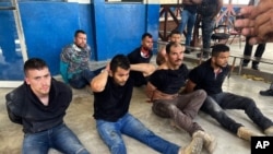Los sospechosos del asesinato del presidente de Haití, Jovenel Moise, sentados en el piso y esposados ​​después de ser detenidos, en la Dirección General de la policía en Puerto Príncipe, el 8 de julio de 2021.