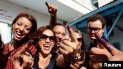 Des Tunisiens montrent leurs doigts colorés après avoir exprimé leur voix, à Tunis le 26 octobre 2014. 