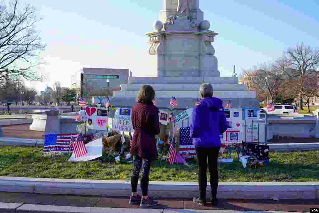 Dos mujeres observan un monumento improvisado en honor a Brian Sicknick, el agente de policía del Capitolio que murió después de ser golpeado por personas que asaltaron el edificio.