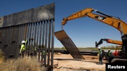 Para pekerja konstruksi tampak dekat peralatan berat saat mengerjakan pilar-pilar dinding yang baru di Santa Teresa, New Mexico, sebagaimana tampak dari sisi Meksiko di perbatasan di San Jeronimo, di pinggiran Ciudad Juarez, Meksiko, 23 April 2018 (foto: Reuters/Jose Luis Gonzale