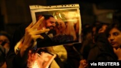 A woman holds a picture of newlyweds, victims of the crash of the Boeing 737-800 plane, Flight 752, as people gather to show their sympathy in Tehran, Iran, Jan. 11, 2020.