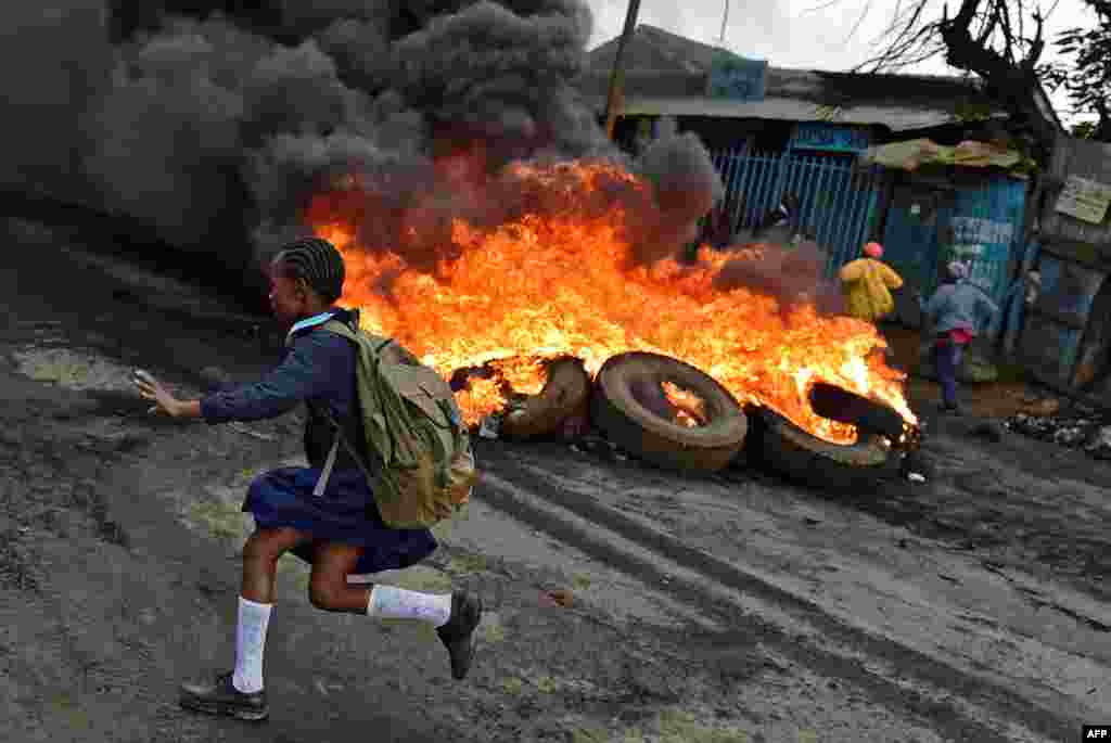 A schoolgirl runs past a burning barricade in Kibera slum in Nairobi, Kenya, during a demonstration of opposition supporters protesting for a change of leadership ahead of next year's election.