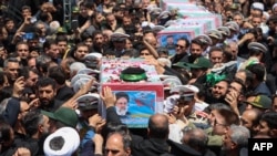 Tentara Iran membawa peti jenazah mendiang presiden Iran Ebrahim Raisi dan pejabat lainnya, sementara ribuan warga ikut menghadiri prosesi pemakaman di kota timur Birjand, hari Kamis 23 Mei 2024.