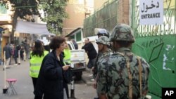 A woman enters a polling station guarded by soldiers and police during the first round of Egypt's run-off parliamentary elections in Cairo, December 5, 2011.
