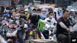 在這張日期為 2021 年 7 月 2 日星期五的文件照片中，北京高峰時段騎自行車和踏板車的人們等待穿過十字路口。聯合國氣候變化官員於 2021 年 7 月 31 日星期六表示，中國未能提交減少溫室氣體排放的新目標，其中數十個未能在 7 月 31 日截止日期前提供其計劃的最新信息。 （美聯社照片）