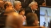 Yehiya Sinwar, left, a top Hamas official in Gaza, holds his son's Ibrahim, while sitting near Ismail Haniyeh, right, a former top Hamas official in Gaza, while listening to Khaled Mashaal, the outgoing Hamas leader in exile, during his news conference in Doha, Qatar, while display on a screen in Gaza City, May 1, 2017. Hamas unveiled what had been billed as a new, seemingly more pragmatic political program. 