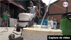 Personas esperan para llenar recipientes con agua de un grifo. Caracas, Venezuela. Febrero, 2021. Foto: captura de video.