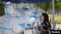 Seorang petugas kesehatan sedang melakukan tes usap pada seorang warga menyusul wabah virus corona (Covid-19) yang merebak kembali di Beijing, China, 20 Juni 2020.
