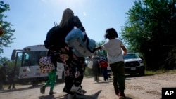 Una familia migrante de Venezuela se dirige al vehículo de la Patrulla Fronteriza después de que cruzaron la frontera entre EE. UU. y México, en Del Rio, Texas, el 16 de junio del 2021.