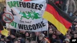 La Droite manifeste avec une banderolle "des réfugiés violeurs" ne sont pas les bienvenus - !Restez chez vous!" et un signe d'une mosquée barrée pendant leur marche a Cologne, Allemagne, samedi le 9 Janvier, 2016. Les femmes activistes de droite , des manifestants d'extrême-droite et de gauche, les contre- manifestants, sont tous descendus dans les rues de Cologne le samedi à la suite d'une vague de vols et d'agressions sexuelles du Nouvel An à Cologne blâmé en grande partie sur les étrangers . ( AP Photo / Juergen Schwarz )