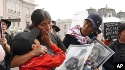 ARCHIVO - Frank Apaza consuela a su madre Asunta Jumpiri, quien sostiene un cartel de su difunto hijo Brayan Apaza, muerto en una protesta exigiendo elecciones y justicia para los asesinados en las protestas tras la salida de Pedro Castillo, en Lima, el 29 de julio de 2023.