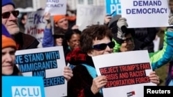 People hold signs during a demonstration against U.S. President Donald Trump on President's day near the White House in Washington, Feb. 18, 2019.