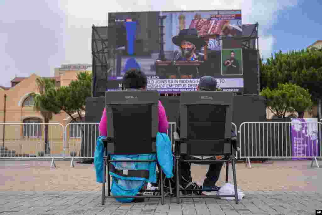 People watch on a large screen the funeral service for Anglican Archbishop Emeritus Desmond Tutu at the St. George's Cathedral in Cape Town, South Africa, Jan.1, 2022.