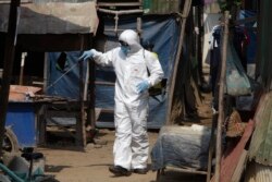 FILE - A member of the non-profit Cambodian Children's Fund sprays disinfectant to help curb the spread of the new coronavirus in the slum neighborhood of Stung Meanchey in southern Phnom Penh, Cambodia, March 24, 2020.