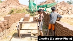 រូបឯកសារ៖ ក្មេងប្រុសពីរនាក់កំពុងលើដុំឥដ្ឋដាក់លើរទេះឈើមួយ នៅសិប្បកម្មឡឥដ្ឋមួយកន្លែងនៅប្រទេសកម្ពុជា។ (រូបថតដោយ Licadho)