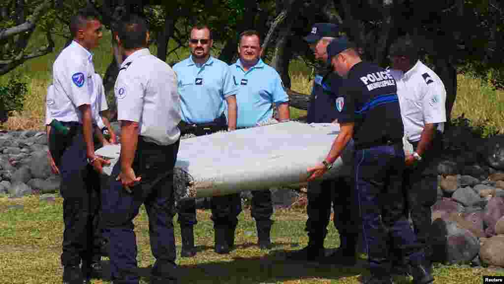 Des gendarmes et policiers français portent un morceau d'avion trouvé sur la plage de Saint-André, 29 juillet 2015.