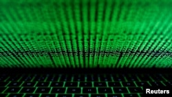 FILE - This photo illustration shows a computer keyboard lit by displayed cyber code.