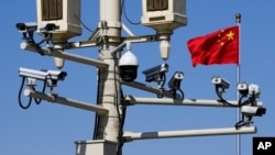Una bandera china ondea cerca de cámaras de vigilancia montadas sobre un poste de luz en la plaza de Tiananmen, en Beijing.