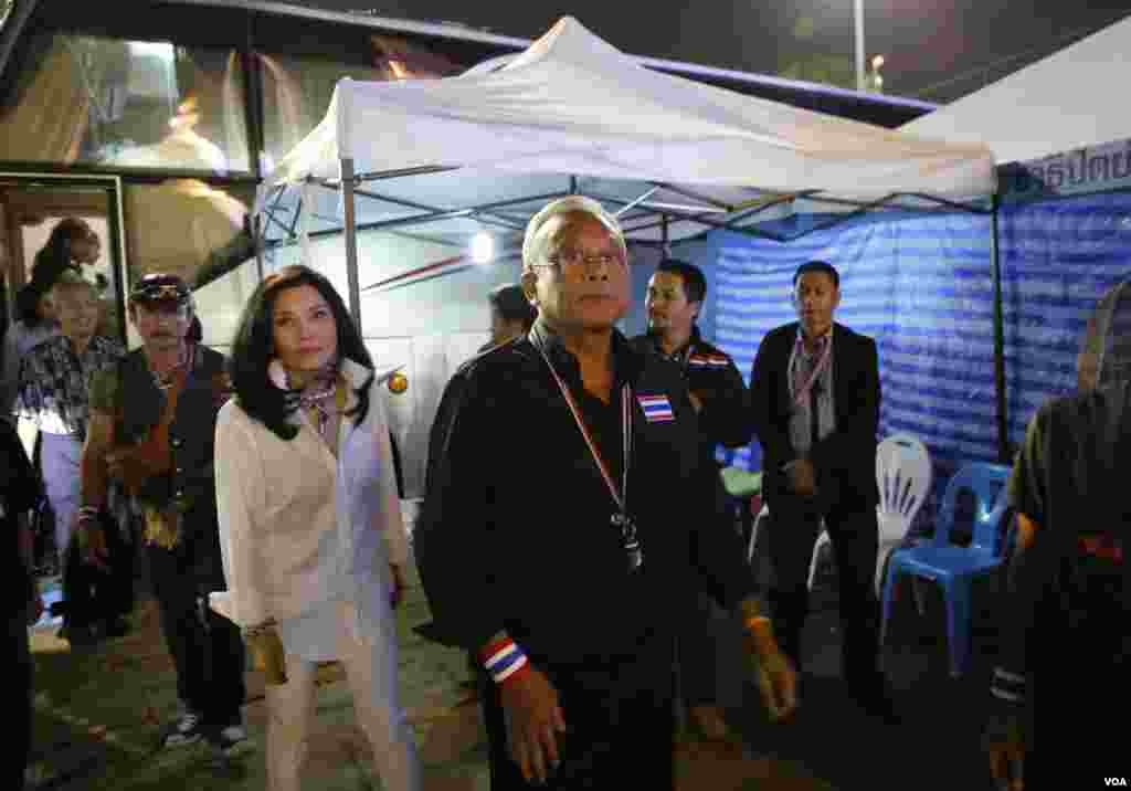 Anti-government protest leader Suthep Thaugsuban, center, with his wife Srisakul Promphan, in white, arrives at the Democracy monument, in Bangkok, Thailand, Dec. 15, 2013. 